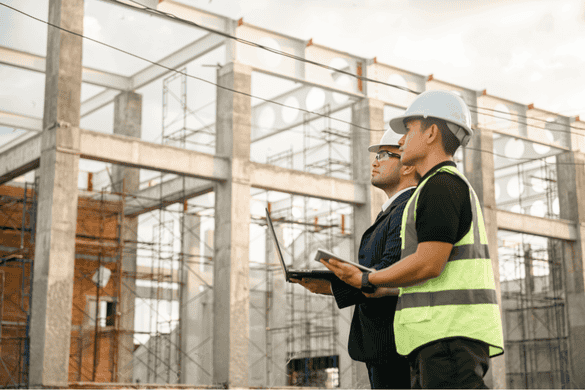 two construction workers looking over a project plan while on a busy worksite